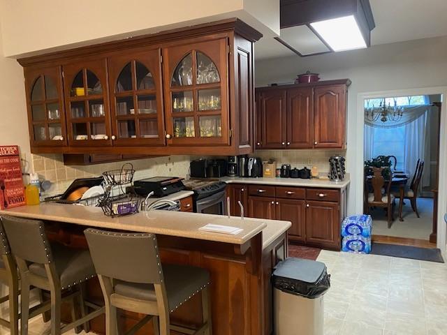 kitchen with tasteful backsplash, kitchen peninsula, a breakfast bar, and stainless steel range with electric stovetop