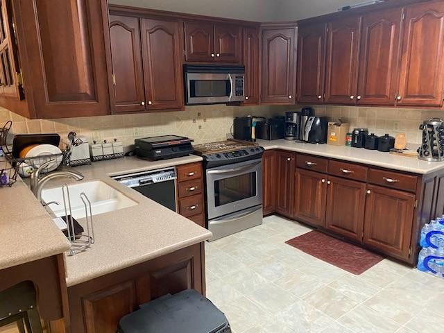 kitchen featuring stainless steel appliances, tasteful backsplash, and sink