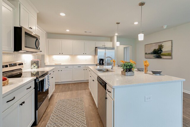 kitchen featuring sink, an island with sink, light hardwood / wood-style flooring, and appliances with stainless steel finishes