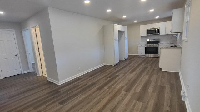 kitchen with white cabinets, sink, dark hardwood / wood-style floors, light stone countertops, and stainless steel appliances