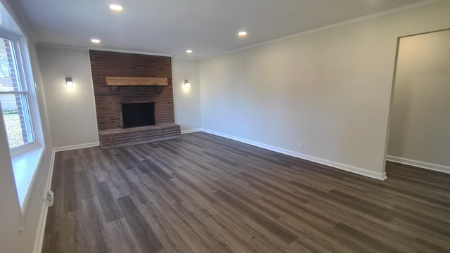 unfurnished living room featuring dark hardwood / wood-style flooring, crown molding, and a brick fireplace