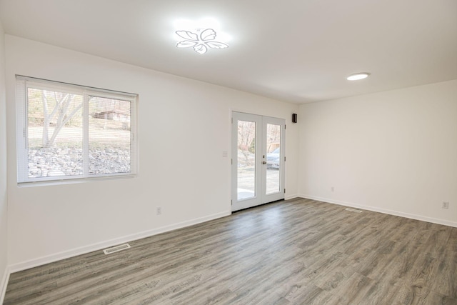 unfurnished room with french doors, a wealth of natural light, and wood-type flooring