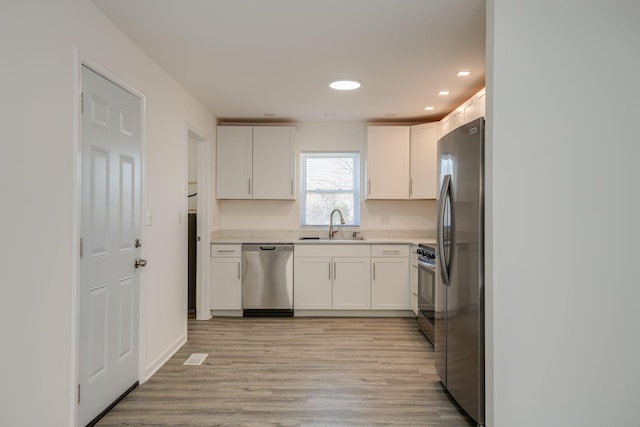 kitchen featuring sink, white cabinets, stainless steel appliances, and light hardwood / wood-style floors