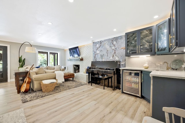 living room with a fireplace, crown molding, beverage cooler, and light hardwood / wood-style flooring