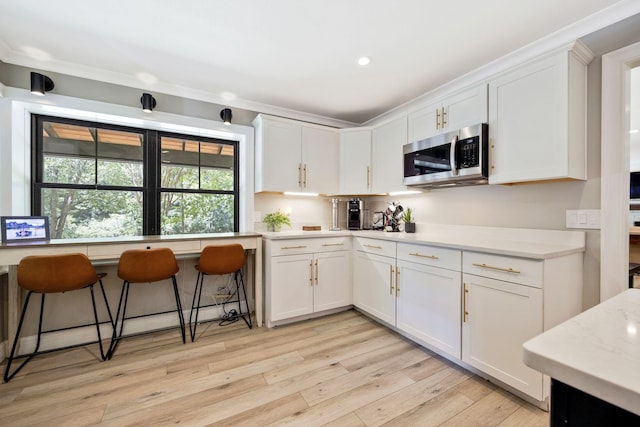 kitchen with a kitchen breakfast bar, white cabinetry, and light wood-type flooring