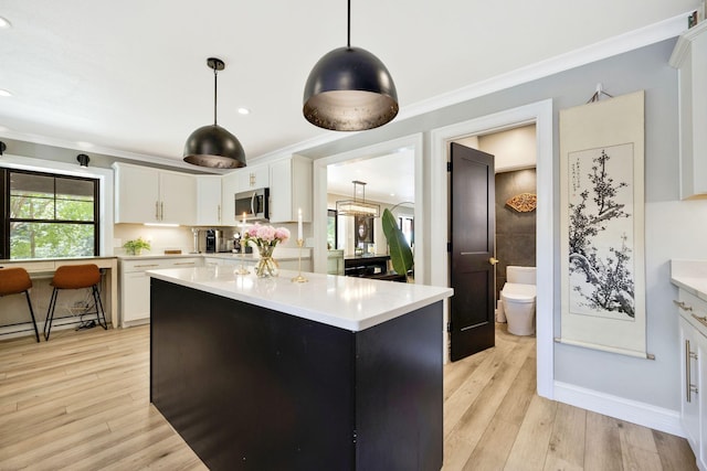 kitchen with a center island, light hardwood / wood-style flooring, white cabinets, and pendant lighting