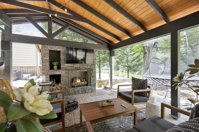 sunroom / solarium with a fireplace, lofted ceiling with beams, plenty of natural light, and wood ceiling