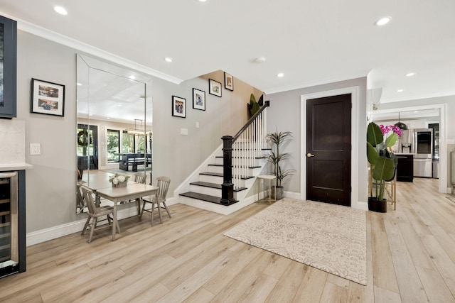 entrance foyer with light wood-type flooring, ornamental molding, and wine cooler