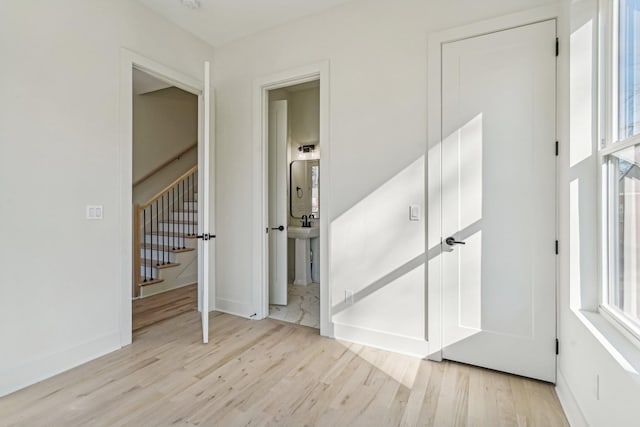 unfurnished bedroom featuring ensuite bathroom and light wood-type flooring