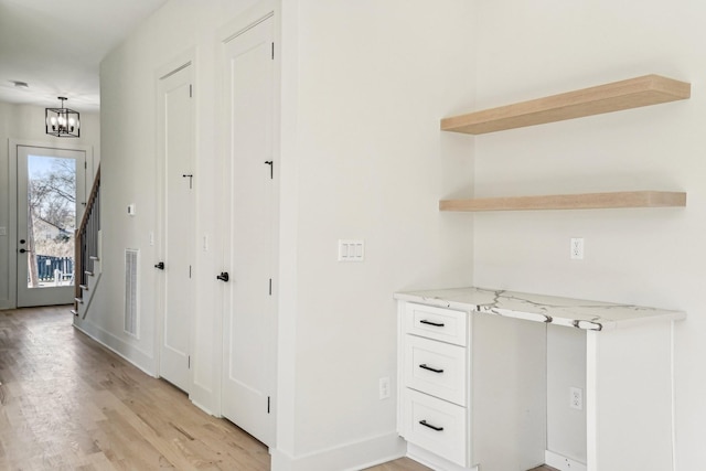 corridor featuring light hardwood / wood-style floors and a notable chandelier