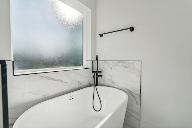 bathroom featuring a washtub and tile walls