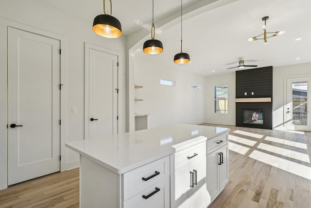 kitchen featuring a fireplace, decorative light fixtures, white cabinetry, and a wealth of natural light