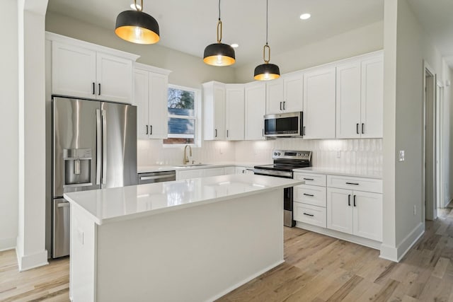 kitchen with white cabinets, a kitchen island, appliances with stainless steel finishes, and pendant lighting