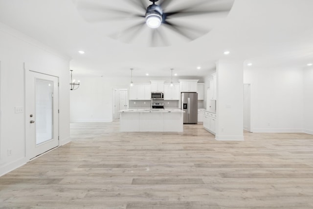 kitchen featuring white cabinetry, stainless steel appliances, decorative light fixtures, a center island with sink, and light wood-type flooring