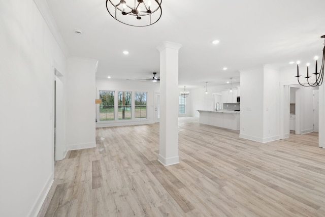 unfurnished living room with ceiling fan, sink, crown molding, and light wood-type flooring