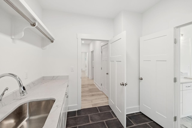 kitchen featuring white cabinets, light stone countertops, sink, and dark wood-type flooring