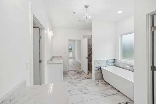 bathroom with vanity, a healthy amount of sunlight, a tub, and a chandelier