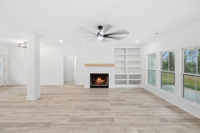 unfurnished living room with ceiling fan with notable chandelier, built in features, light wood-type flooring, and ornamental molding