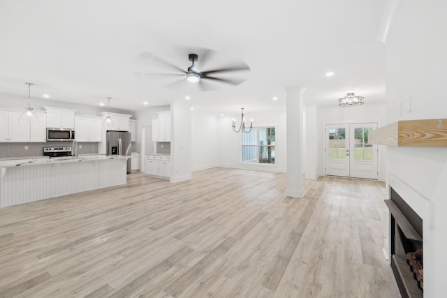 unfurnished living room featuring french doors, light hardwood / wood-style flooring, and ceiling fan with notable chandelier