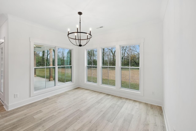 unfurnished dining area with ornamental molding, a chandelier, and light hardwood / wood-style floors