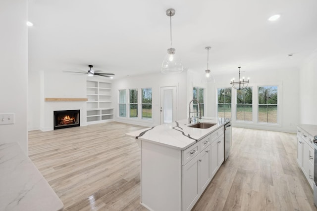 kitchen with plenty of natural light, stainless steel dishwasher, decorative light fixtures, and sink