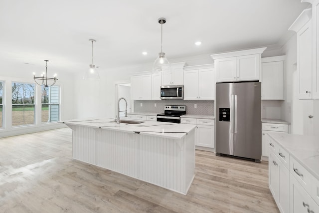 kitchen with hanging light fixtures, stainless steel appliances, light hardwood / wood-style floors, a kitchen island with sink, and white cabinets