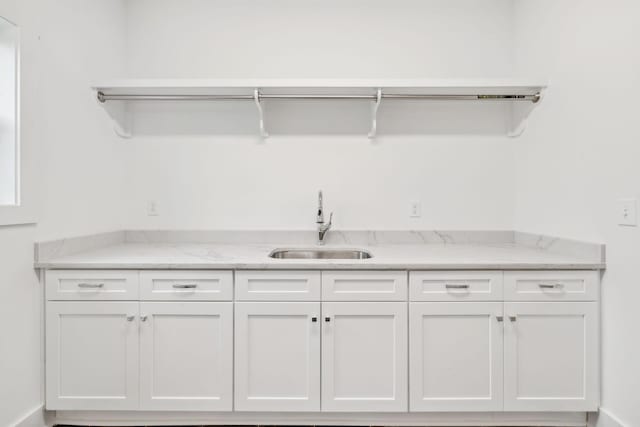 interior space featuring white cabinetry, sink, and light stone counters