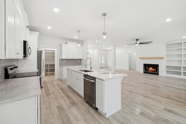 kitchen featuring sink, white cabinets, stainless steel appliances, and decorative light fixtures