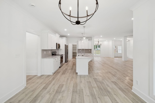 kitchen with white cabinetry, stainless steel appliances, tasteful backsplash, an island with sink, and light wood-type flooring