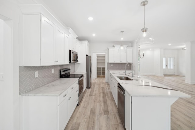 kitchen featuring appliances with stainless steel finishes, sink, decorative light fixtures, light hardwood / wood-style flooring, and white cabinets