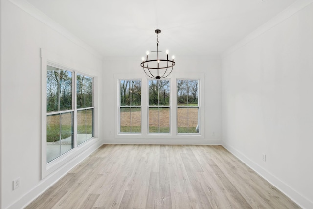 unfurnished dining area featuring light hardwood / wood-style flooring, an inviting chandelier, and crown molding