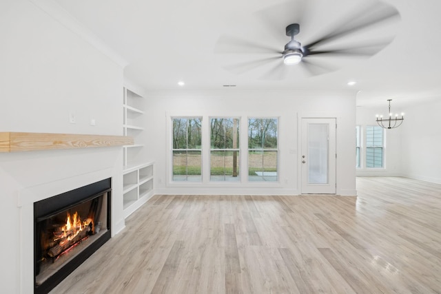 unfurnished living room with built in shelves, crown molding, light hardwood / wood-style flooring, and ceiling fan with notable chandelier