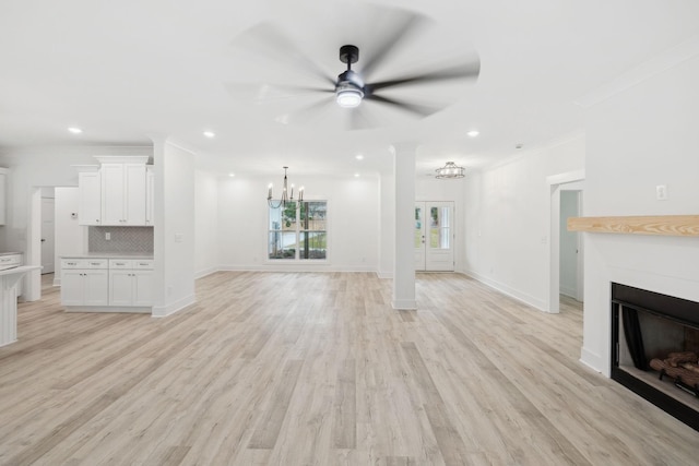 unfurnished living room with ceiling fan with notable chandelier, light hardwood / wood-style flooring, and crown molding