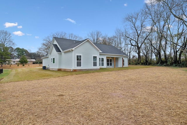 rear view of property featuring a lawn and central air condition unit