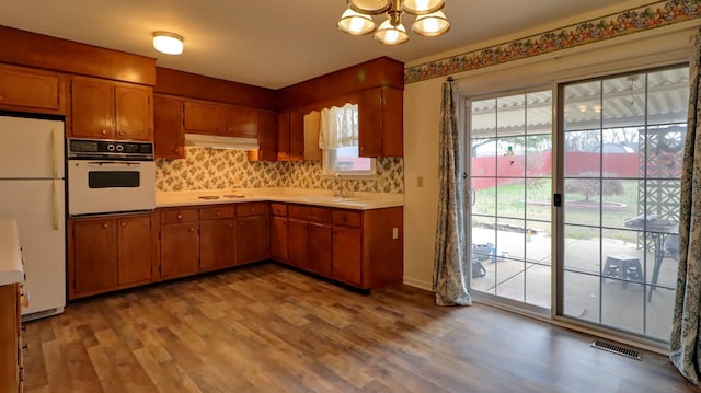 kitchen with tasteful backsplash, light hardwood / wood-style flooring, white appliances, and sink