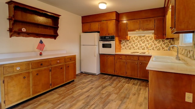 kitchen with backsplash, light wood-type flooring, white appliances, and sink