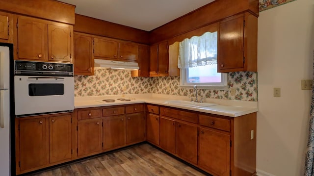 kitchen featuring light wood-type flooring, decorative backsplash, white appliances, and sink