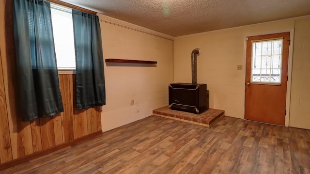 unfurnished living room with a wood stove, crown molding, hardwood / wood-style floors, and a textured ceiling