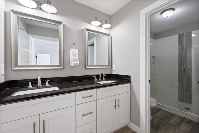 bathroom with vanity, hardwood / wood-style flooring, toilet, and a shower with door