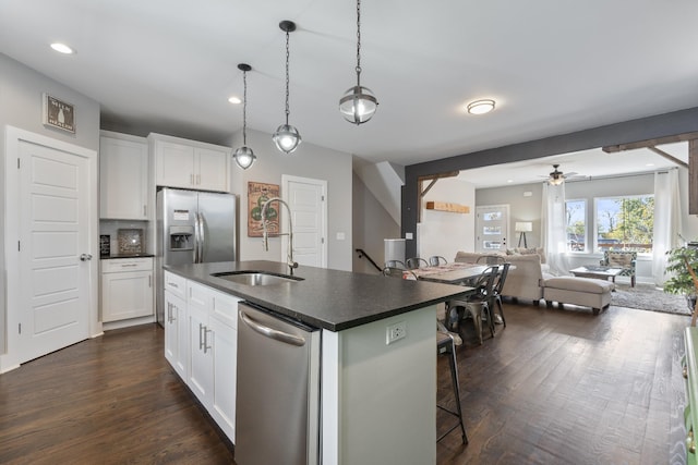 kitchen with white cabinets, ceiling fan, a center island with sink, and appliances with stainless steel finishes