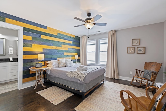 bedroom with ceiling fan, ensuite bathroom, and dark wood-type flooring