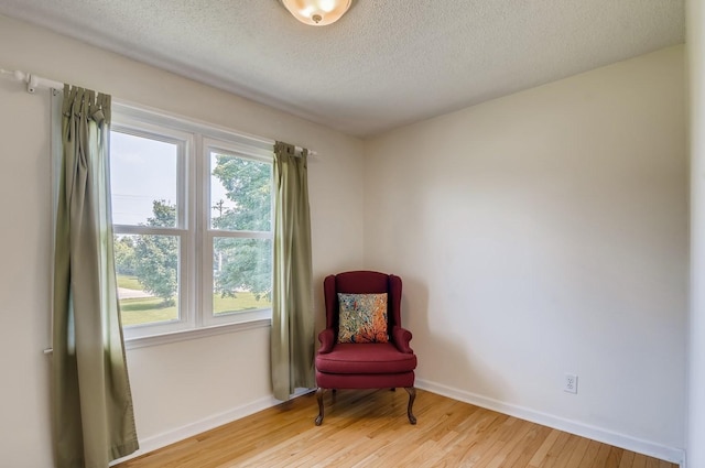 sitting room with a textured ceiling, light wood-type flooring, and a healthy amount of sunlight