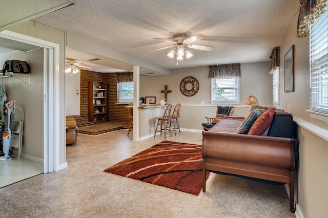 carpeted living room featuring ceiling fan, a textured ceiling, and brick wall