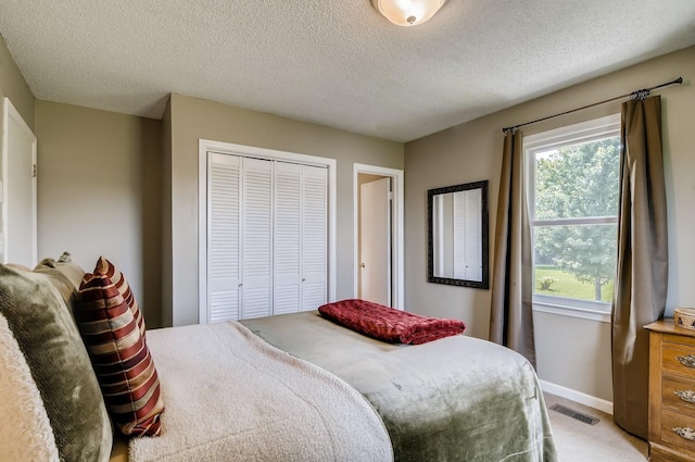 carpeted bedroom with a textured ceiling and a closet