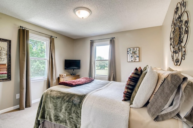 carpeted bedroom featuring multiple windows and a textured ceiling