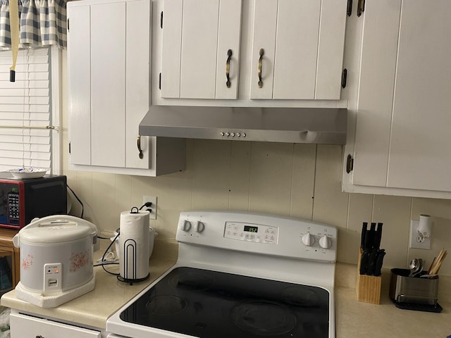 kitchen featuring white cabinets, white range, and ventilation hood