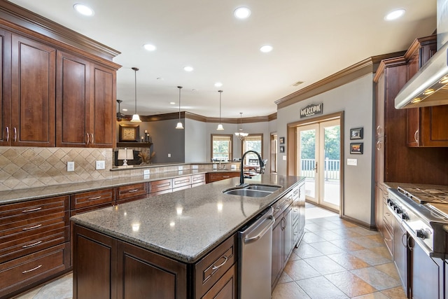 kitchen with sink, french doors, hanging light fixtures, an island with sink, and decorative backsplash