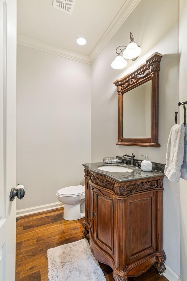 bathroom featuring vanity, toilet, wood-type flooring, and ornamental molding