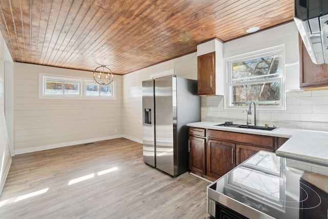 kitchen featuring stainless steel fridge, sink, light hardwood / wood-style floors, and backsplash