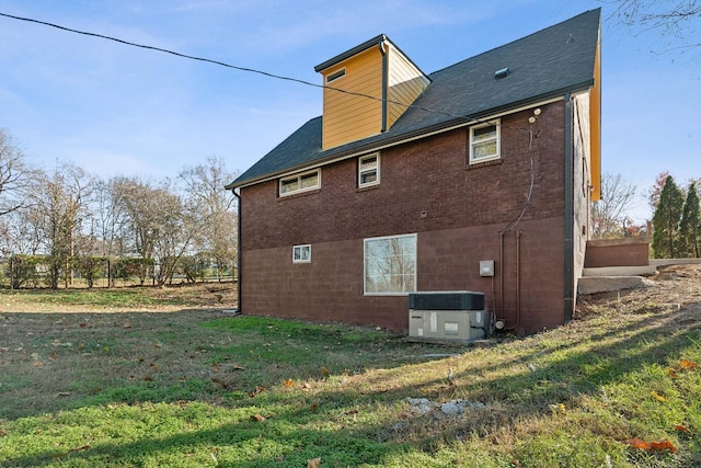 back of house featuring central air condition unit and a yard